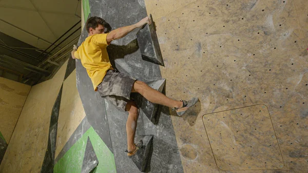Młody człowiek trenuje do zawodów w skałach w zamkniętym obiekcie wspinaczkowym. — Zdjęcie stockowe