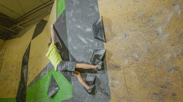 ESPACE DE COPIE : Un jeune homme athlétique s'accroche au bord d'une grande prise de volume noire — Photo