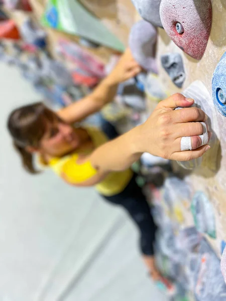 VERTICAL, DOF: Fit young Caucasian woman reaches up to grip a yellow jug hold. — Stock Photo, Image