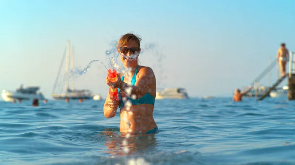 PORTRAIT: Leende ung kvinna njuter av sin sommarsemester skjuter en vattenpistol. — Stockfoto