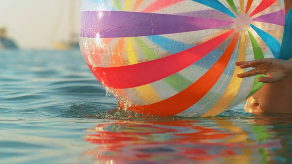 A bikinis nő felfújható labdát pörget a tenger felszínén. — Stock Fotó