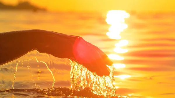 L'acqua sgorga dalla mano di una donna mentre la solleva dall'oceano. — Foto Stock