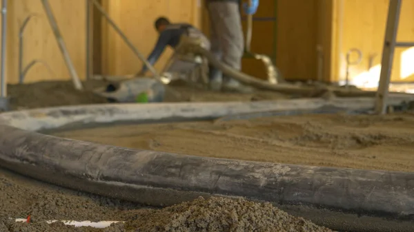 CLOSE UP: Rubber slang pulsaten als aannemers gieten beton over de grond. — Stockfoto