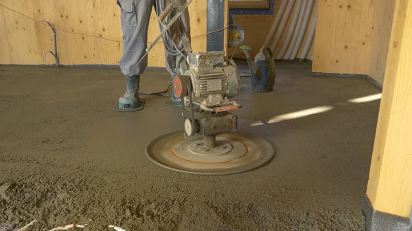 CLOSE UP: Opdrachtnemer gebruikt een buffer om beton gladstrijken de grond. — Stockfoto