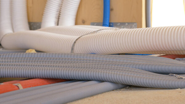 CLOSE UP: Corrugated tubing runs along the ground of a house under construction.