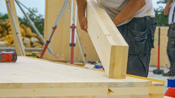 CLOSE UP: Unbekannter männlicher Bauarbeiter hebt einen CLT-Balken von einer Werkbank auf. — Stockfoto