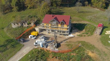 Büyük bir matkap, bir CLT konut projesinin yanında yerdeki bir deliği sıkıyor..