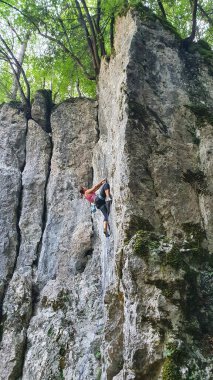 Güçlü bir kadın mükemmel bir bahar gününde zorlu bir kayalık duvara tırmanır..