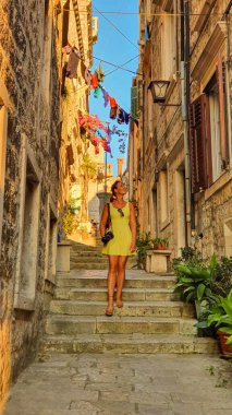 Genç bayan fotoğrafçı Korcula 'da güneş ışığıyla aydınlanan sokaklarda dolaşıyor.