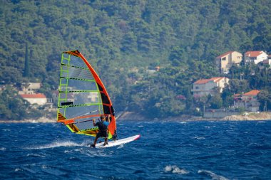 Tanınmayan adam Hırvatistan 'ın huzurlu Akdeniz kıyısından rüzgar sörfü yaparak geçti.