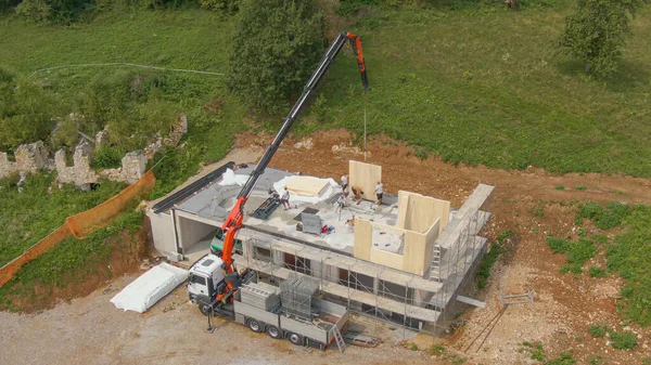 AERIAL: Truck boom operator helps contractors working on building CLT house. — ストック写真