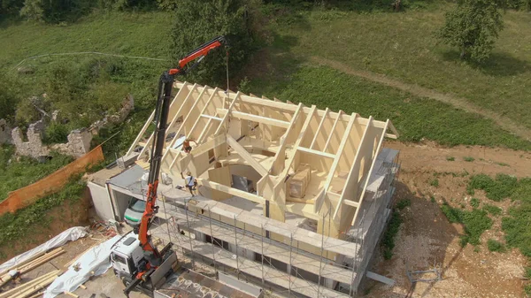 AERIAL: As vigas são levantadas enquanto os trabalhadores montam o telhado da casa pré-fabricada. — Fotografia de Stock