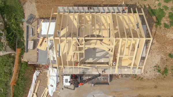 TOP DOWN vigas são levantadas enquanto os trabalhadores montam o telhado da casa pré-fabricada — Fotografia de Stock