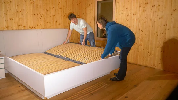 FERMER : Les jeunes couples travaillent ensemble pour assembler un grand lit dans leur nouvelle maison. — Photo