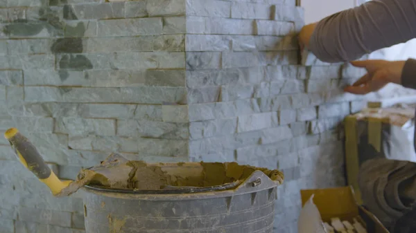 ZAMKNIJ: Budowniczy mierzy kamienną płytkę układając płytki na ścianie. — Zdjęcie stockowe