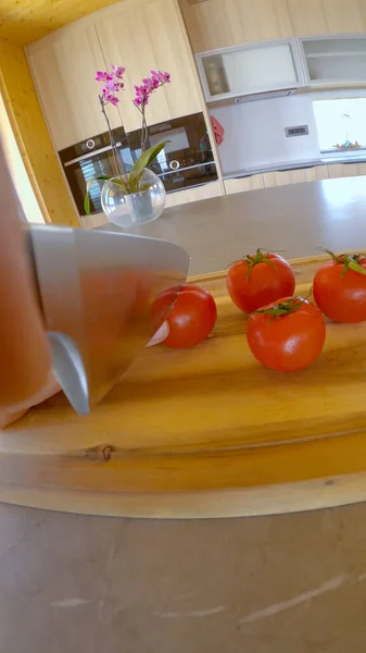 VERTICAL : Couteau de chef tranchant coupe une délicieuse tomate biologique en petits quartiers. — Photo