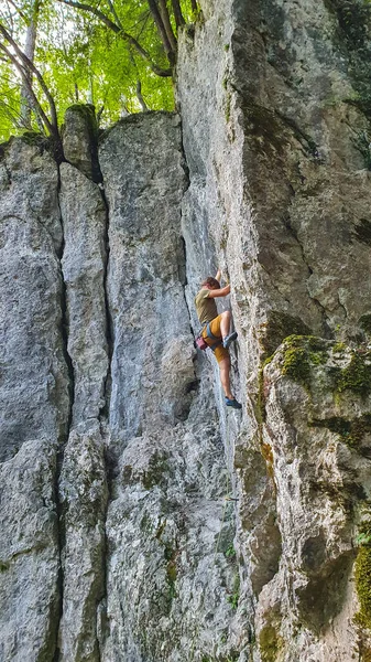 VERTICAL: Adrenalina procurando jovem sobe um penhasco em uma floresta tranquila. — Fotografia de Stock