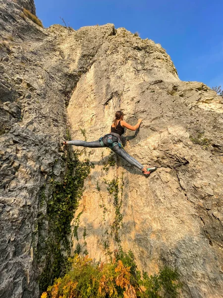VERTICAL: Agile female rock climber almost does the splits while climbing. — Stock Photo, Image