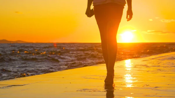 LOW ANGLE: Attractive woman wearing heels walks along the wet sunlit promenade. — Stock Photo, Image