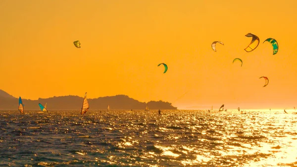 Innumerables kitesurfistas y windsurfistas están montando olas cerca de Peljesac al atardecer. — Foto de Stock