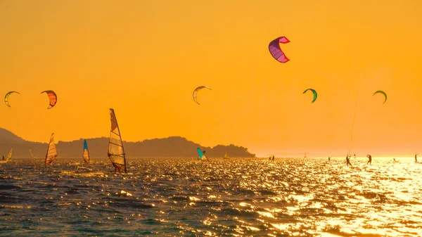 Los turistas enérgicos están haciendo windsurf en la costa de Croacia en una soleada noche de verano. — Foto de Stock