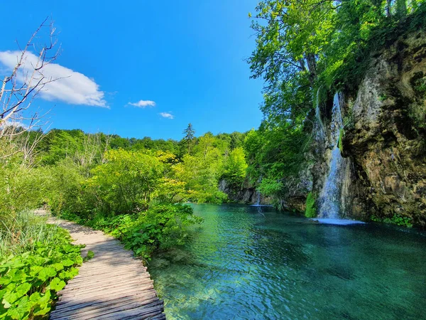 Üres sétány fut át egy kis vízesés a festői Plitvice Nemzeti Park — Stock Fotó