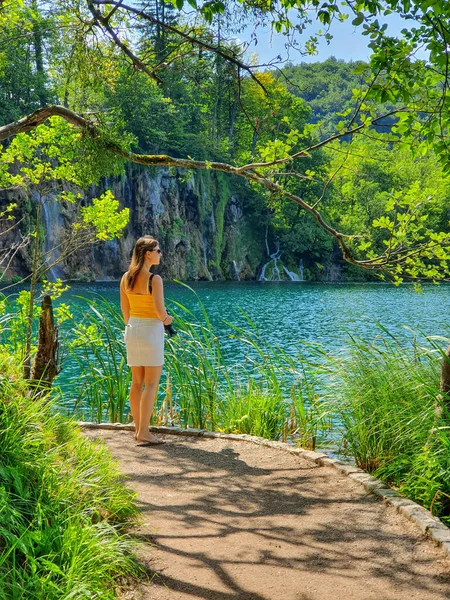 VERTICAL: Vrouwelijke toerist zoekt inspiratie voor fotografie in Plitvice park. — Stockfoto