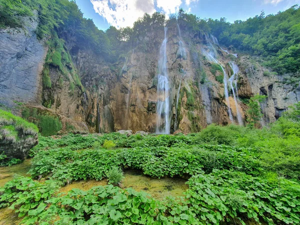 LOW ANGLE: Saftig grüne Vegetation bedeckt die Ausläufer eines massiven Wasserfalls. — Stockfoto