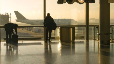 Diğer yolcular hızla geçerken, turistler pisti ve uçakları gözlemliyor.