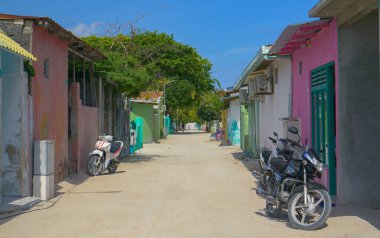 Maldivler 'deki renkli evlerin önünden geçen boş toprak yolun manzarası