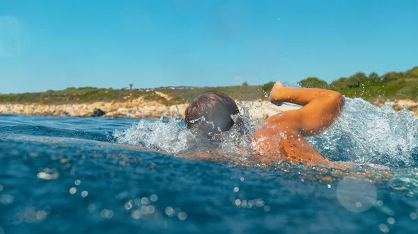 CHIUSURA: Giovane turista di sesso maschile va a fare una nuotata per rinfrescarsi in una giornata estiva soleggiata. — Foto Stock