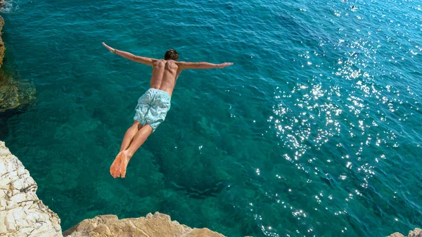 Man hoppar från en klippavsats och in i det glittrande blå havet.. — Stockfoto