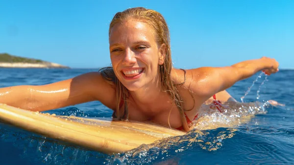 CERRAR: Hermosa chica surfista caucásica sonríe mientras reman hacia fuera para alinearse. —  Fotos de Stock
