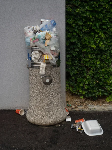 VERTICALE : Des gens irréfléchis laissent des ordures sur le dessus et autour de la poubelle débordante. — Photo
