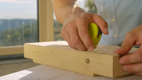 CHIUSURA: Costruttore irriconoscibile utilizza un metro a nastro per ispezionare un blocco di legno. — Foto Stock