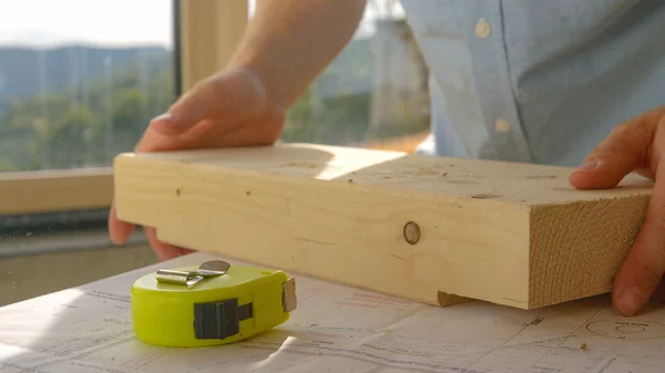 CERRAR: El contratista recoge un bloque de madera después de medirlo con cinta métrica — Foto de Stock