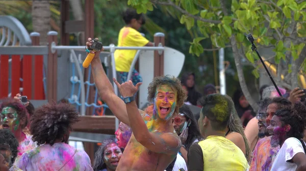 CLOSE UP: Cheerful tourist gives the shaka sign while dancing at a holi festival — Stock Photo, Image
