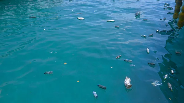 ZAMKNIJ: Puste plastikowe butelki pływają wokół spokojnego turkusowego oceanu. — Zdjęcie stockowe