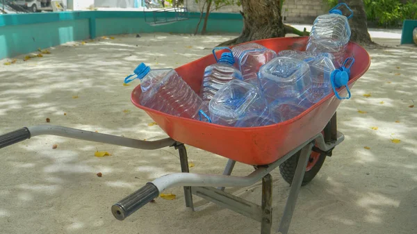 FECHAR UP: Carrinho de mão é preenchido com garrafas como as pessoas esperam pela entrega de água. — Fotografia de Stock