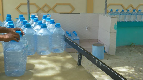 CERRAR: El hombre local recoge contenedores de galones vacíos durante la entrega de agua —  Fotos de Stock