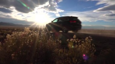 Sabah güneşleri Amerika 'da tozlu bir yolda giden bir arabada parlıyor..