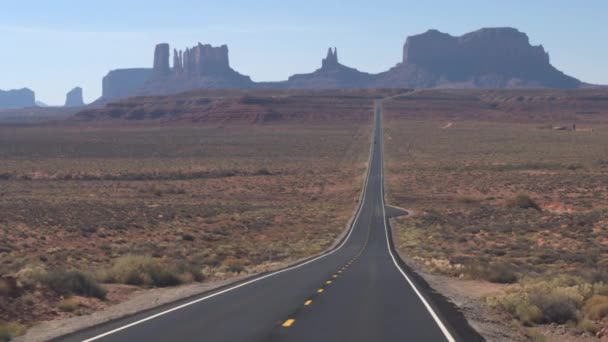 Mobil hitam yang jauh berkendara menjauh dari Monumen Valley yang spektakuler. — Stok Video