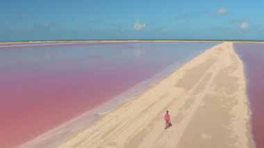 Yucatan 'daki canlı pembe tuz çiftliğini keşfeden bir kadının insansız hava aracı görüntüsü..