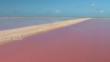 Meksika 'nın tuz tarlalarında manzaralı toprak bir yolda yürüyen bir kadın..