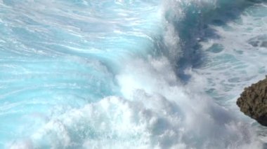 Turkuaz okyanus dalgaları Bali 'deki siyah bir volkanik kayanın üzerinde kırılıyor..