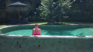 Bali 'de tatilde olan bir kadın etkin, ormanı havuzdan gözlüyor..