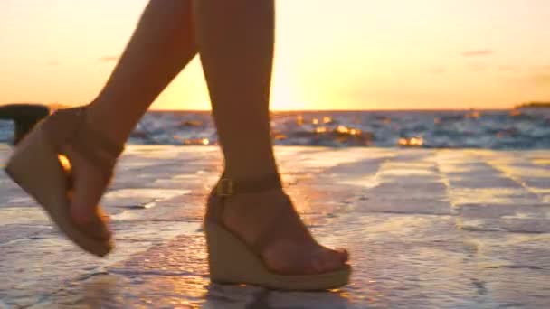 LOW ANGLE: Female tourist goes for a stroll along the idyllic shore at sunset. — Stock Video