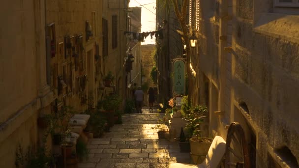 LENS FLARE: Malá skupina turistů procházky po malebné ulici v Korčule. — Stock video