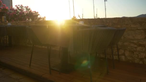 LENS FLARE: Prázdný jídelní stůl v Korčule s výhledem na sluncem ozářenou luxusní jachtu. — Stock video