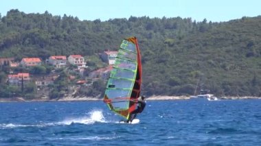 Tanınmayan adam Hırvatistan 'ın huzurlu Akdeniz kıyısından rüzgar sörfü yaparak geçti.